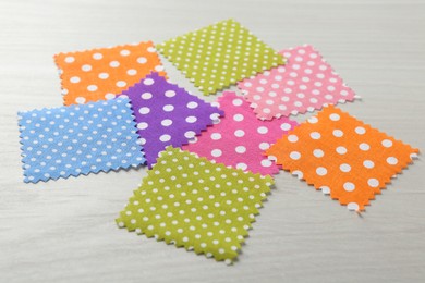 Photo of Samples of different fabrics on white wooden table, closeup