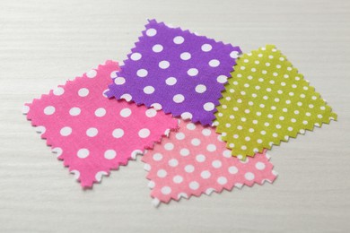 Photo of Samples of different fabrics on white wooden table, closeup