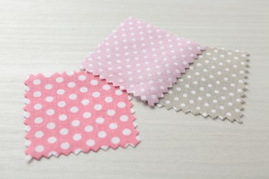 Photo of Samples of different fabrics on white wooden table, closeup