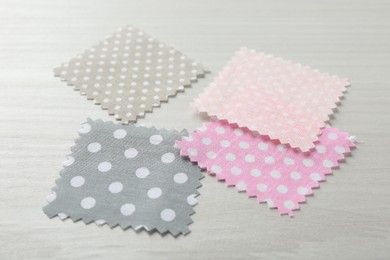 Photo of Samples of different fabrics on white wooden table, closeup