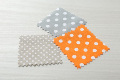 Photo of Samples of different fabrics on white wooden table, closeup