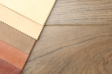Photo of Samples of different fabrics on wooden table, top view. Space for text