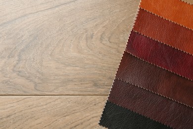 Photo of Samples of different fabrics on wooden table, top view. Space for text