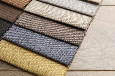 Photo of Samples of different fabrics on wooden table, closeup