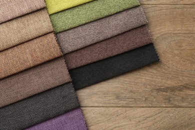 Photo of Samples of different fabrics on wooden table, top view