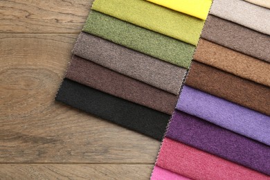 Photo of Samples of different fabrics on wooden table, top view