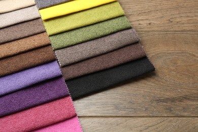 Photo of Samples of different fabrics on wooden table, closeup