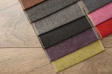 Photo of Samples of different fabrics on wooden table, top view