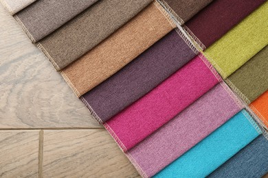 Photo of Samples of different fabrics on wooden table, top view