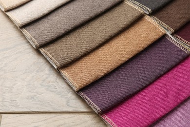 Photo of Samples of different fabrics on wooden table, closeup