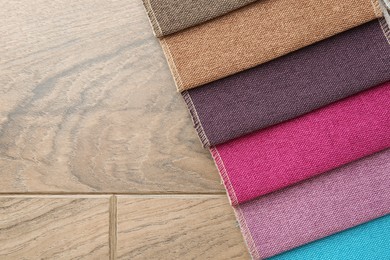 Photo of Samples of different fabrics on wooden table, top view. Space for text