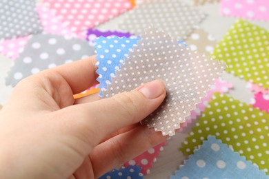 Photo of Woman with samples of different fabrics on white wooden table, closeup