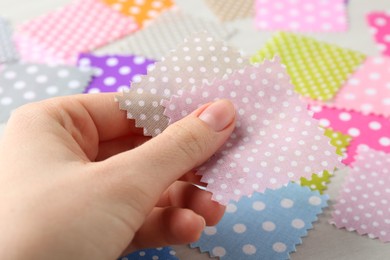 Photo of Woman with samples of different fabrics on white wooden table, closeup