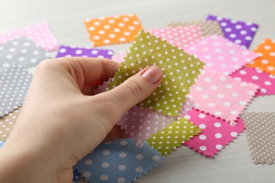 Photo of Woman with samples of different fabrics on white wooden table, closeup