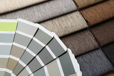 Photo of Samples of different fabrics and color selection chart as background, closeup