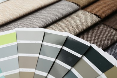 Photo of Samples of different fabrics and color selection chart as background, closeup