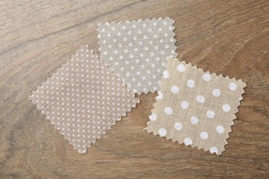 Photo of Samples of different fabrics on wooden table, flat lay