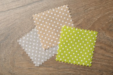Photo of Samples of different fabrics on wooden table, flat lay