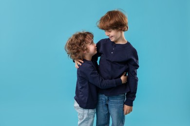 Photo of Cute little brothers hugging on light blue background