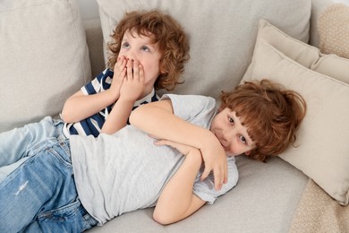 Photo of Cute little brothers laying together on sofa