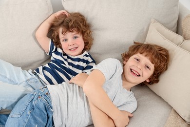 Photo of Cute little brothers laying together on sofa