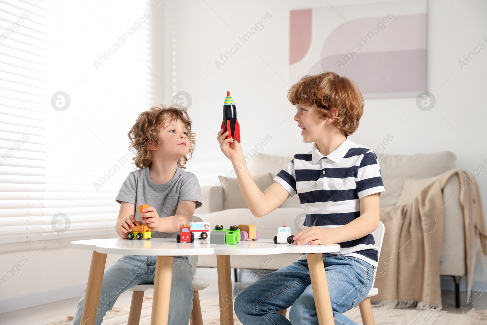 Cute little brothers playing with toys at table indoors Photo of Cute little brothers playing with toys at table indoors