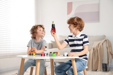 Photo of Cute little brothers playing with toys at table indoors