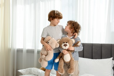 Photo of Cute little brothers with toys on bed at home