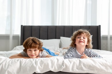 Photo of Cute little brothers laying on bed at home. Space for text
