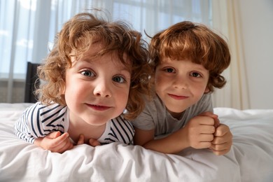 Photo of Cute little brothers laying on bed at home, wide angle