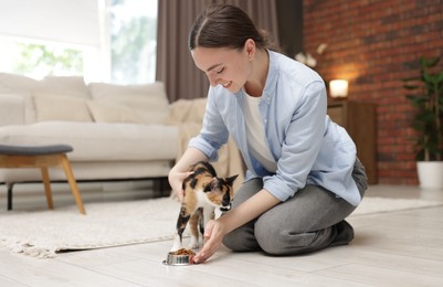 Photo of Woman feeding her cute calico kitten at home