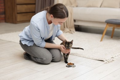 Photo of Woman feeding her cute calico kitten at home