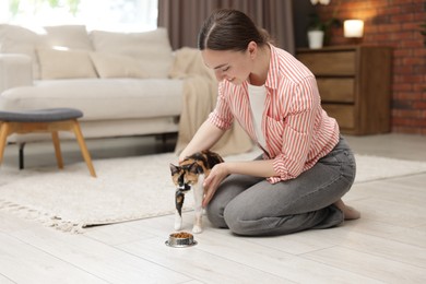 Photo of Woman feeding her cute calico kitten at home