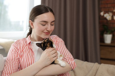 Photo of Woman with her cute calico kitten of sofa at home, space for text