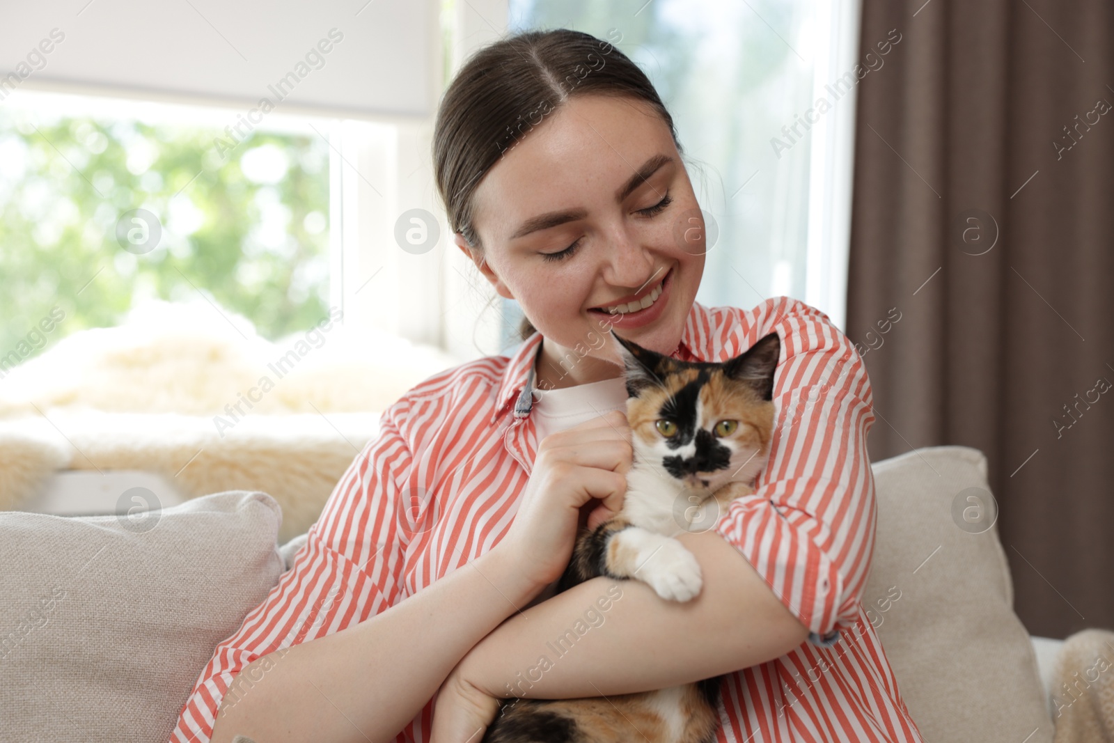 Woman with her cute calico kitten of sofa at home Photo of Woman with her cute calico kitten of sofa at home