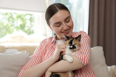 Photo of Woman with her cute calico kitten of sofa at home