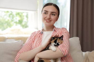 Photo of Woman with her cute calico kitten of sofa at home