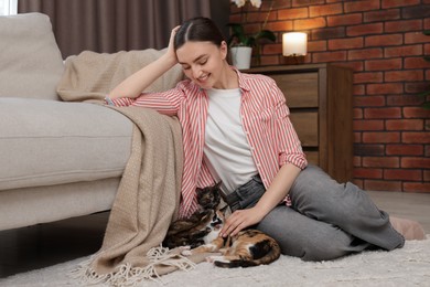 Photo of Woman with her cute calico kittens on floor at home