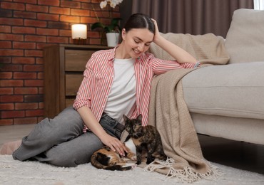 Photo of Woman with her cute calico kittens on floor at home