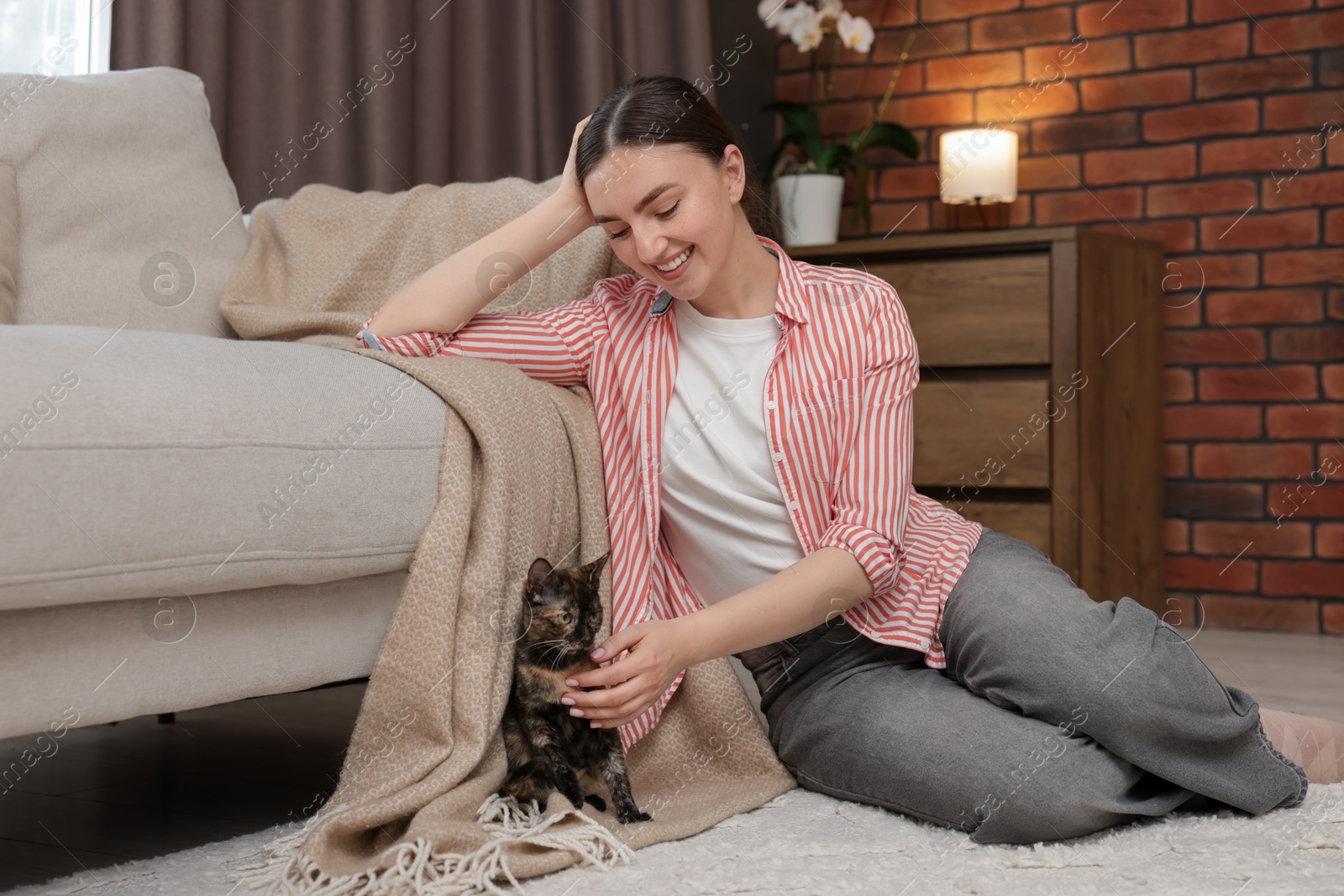 Woman with her cute calico kitten on floor at home Photo of Woman with her cute calico kitten on floor at home