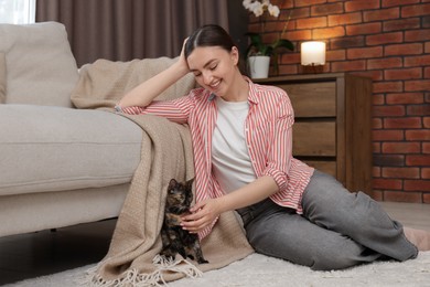 Photo of Woman with her cute calico kitten on floor at home