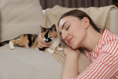 Photo of Woman with her cute calico kitten of sofa at home