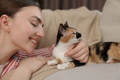 Photo of Woman with her cute calico kitten of sofa at home