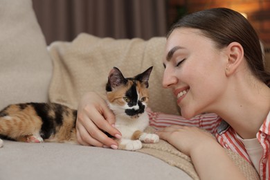 Photo of Woman with her cute calico kitten of sofa at home