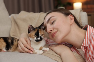 Photo of Woman with her cute calico kitten of sofa at home