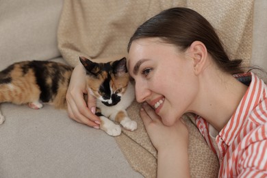 Photo of Woman with her cute calico kitten of sofa at home