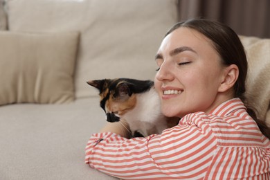 Photo of Woman with her cute calico kitten of sofa at home, space for text