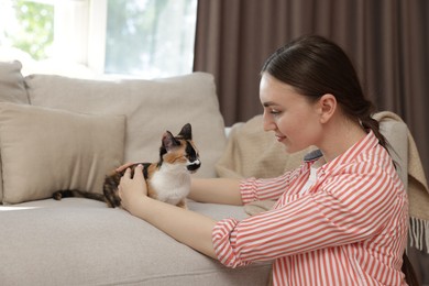 Photo of Woman with her cute calico kitten of sofa at home