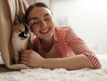 Photo of Woman with her cute calico kitten on floor at home