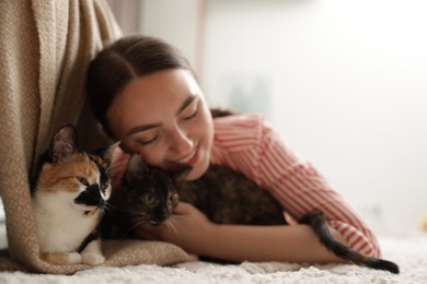 Photo of Woman with her cute calico kittens on floor at home